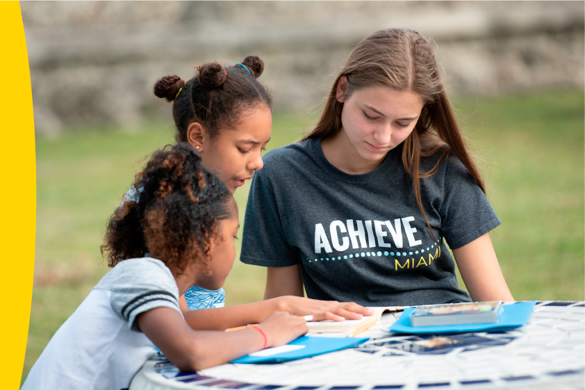High school girl teaching elementary school girls to read