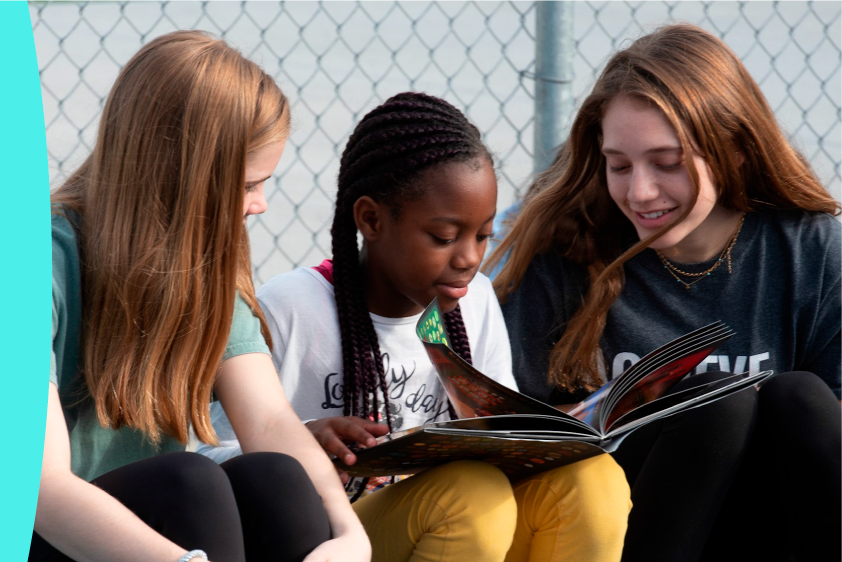 High school girl teaching elementary girl how to read